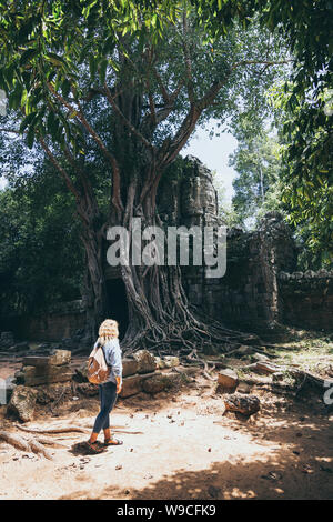 Kaukasische blonde Frau, die Entdeckung der Ruinen von Angkor Wat Tempel Komplex in Siem Reap, Kambodscha. Baum auf dem Dach des Tempels Eingangstor arc Stockfoto