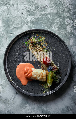 Schwarz cod Steak mit Tomatensauce und Buchweizen Popcorn, Ansicht von oben auf einem Teller. Platz kopieren, grauen Hintergrund. Stockfoto