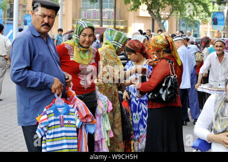 Lokalen chinesischen Uigurischen Shopper kaufen Bekleidung von Straßenverkäufern in Urumqi im Nordwesten Chinas Autonome Region Xinjiang Uygur, 12. Juli 2009. Gesetz und Ord Stockfoto