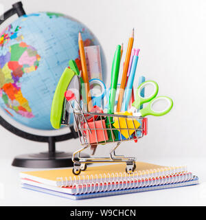 World Globe und Warenkorb mit Schreibwaren auf Weiß Stockfoto