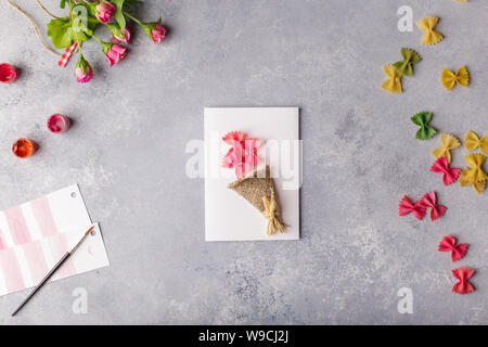 Papier basteln für Muttertag, 8. März oder Geburtstag. Kleines Kind tun einen Blumenstrauß aus farbigem Papier und bunte Nudeln. Stockfoto