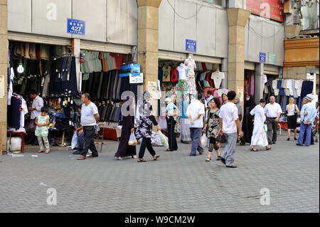 Lokalen chinesischen Uigurischen Bürger vorbei Bekleidung Shops auf einer Straße in Urumqi im Nordwesten Chinas Autonome Region Xinjiang Uygur, 12. Juli 2009. Recht und Stockfoto