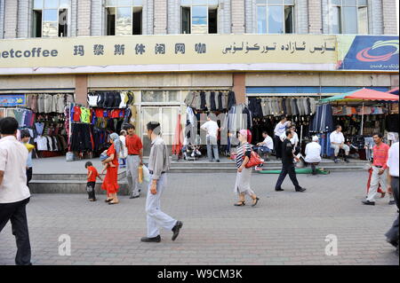 Lokalen chinesischen Uigurischen Bürger vorbei Bekleidung Shops auf einer Straße in Urumqi im Nordwesten Chinas Autonome Region Xinjiang Uygur, 12. Juli 2009. Recht und Stockfoto