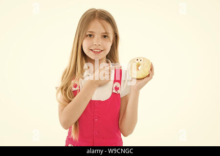 Mädchen mit grossen Lächeln holding Donut. Animierte Dessert, verglaste Bagel mit Augen. Kid zeigen auf süsses, süsses Himmel. Kind mit langem Haar zu tragen rosa Outfit auf weißem Hintergrund. Stockfoto