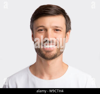 Positive charismatische Mann lächelnd an Kamera auf weißem Hintergrund Stockfoto
