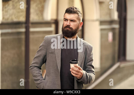 Kaffeegenuss unterwegs. Geschäftsmann gepflegt aussehen genießen Sie Kaffee Pause aus Business Center. Entspannen und erholen Sie sich. Man bärtige hipster Pappbecher Kaffee trinken. Noch ein Schluck Kaffee. Stockfoto