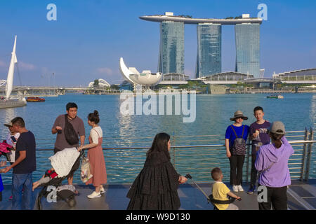 Chinesische Touristen auf Fußgänger Jubilee Bridge für Fotografien mit Marina Bay und die Ikonischen Marina Bay Sands Hotel in der b/g posiert; Singapur Stockfoto