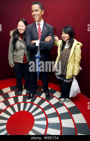 Chinesische Besucher stellen neben einer Wachsfigur von US-Präsident Barack Obama an der Madame Tussauds Wax Museum in Shanghai, China, 16. November 2009. Ein Stockfoto