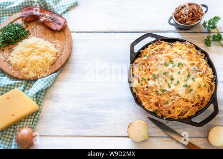 Home Kochen des Bayerischen Spätzle mit Käse und Speck. Oben Ansicht von Zutaten für Deutsche traditionelle Oktoberfest essen Käse Pasta am weißen Tisch Stockfoto