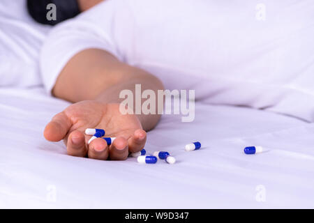 Frau auf dem Bett liegend nach einer Überdosis Pillen zu Hause. Überdosierung und Selbstmord Konzept. Stockfoto