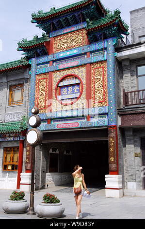 ---- Eine Frau geht hinter einem Quanjude gebratene Ente Restaurant auf der Qianmen Straße in Peking, China, 15. Juli 2009. Quanjude, den berühmten chinesischen roas Stockfoto