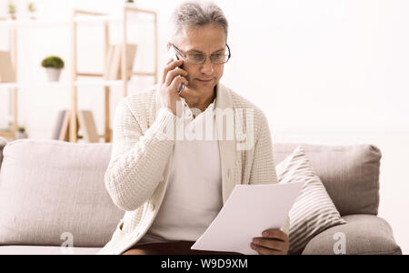 Pensionierter Mann am Telefon sprechen, diskutieren Rechnungen Stockfoto