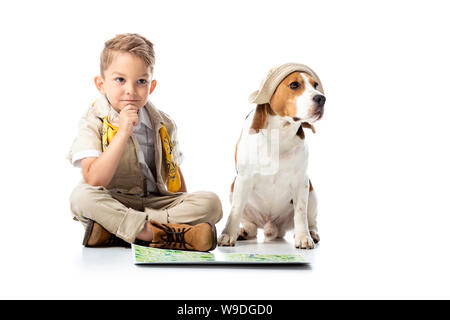 Nachdenklich explorer Kind mit Karte und niedlichen beagle Hund in Hut auf Weiß Stockfoto