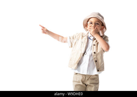 Schockiert explorer Junge in Hut und Brille, die den Mund mit der Hand und zeigte mit dem Finger isoliert auf weißem Stockfoto