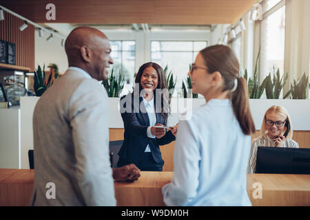 Freundliche junge afrikanische amerikanische Concierge in einem empfangstresen Raum Informationen zu zwei Gäste in einem Hotel arbeiten Stockfoto