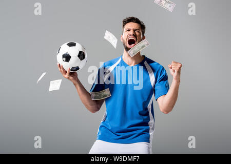 Fußball-Spieler mit Ball Jubel mit geballten Hand in der Nähe des Geldes auf Grau Stockfoto