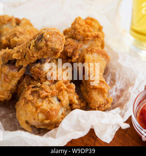 Fried Chicken Drumsticks mit Soße und Glas kaltes Bier, Seitenansicht. Close-up. Stockfoto