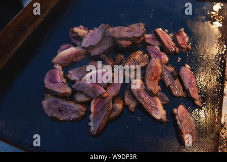 Gebratene Ente auf dem Grill im Freien. Scheiben appetitlich Frisch Fleisch beim Braten. Am Abend. Stockfoto