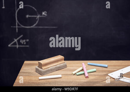 Schreibtisch mit Kreide, Radiergummi und Tafel mit Geometrie Zeichnungen. Bildung o Lernkonzept. Platz kopieren Stockfoto