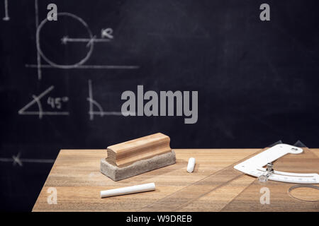 Schreibtisch mit Kreide, Radiergummi und Tafel mit Geometrie Zeichnungen. Bildung o Lernkonzept. Platz kopieren Stockfoto