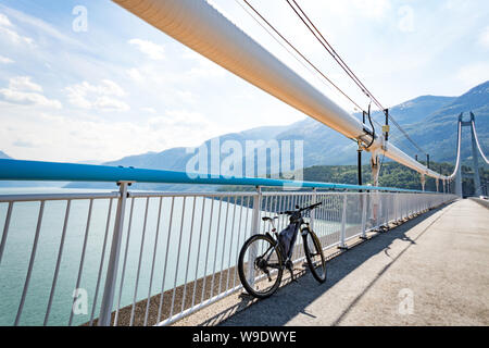 Thema Mountainbiken in Skandinavien. menschliche Tourist in Helm und Sportswear mit dem Fahrrad in Norwegen auf Hardanger Brücke Hängebrücke geworfen Stockfoto