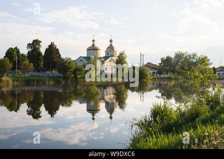 ICHNYA, UKRAINE - 14. MAI 2019. Kirche auf dem Hintergrund der See. Kirche und Wolken sind im Wasser wider. Stockfoto