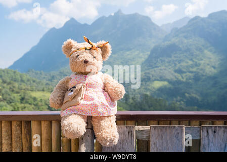 Tragen Puppe sitzend und am Morgen Zeit mit der Natur auf die Berge im Hintergrund entspannen Stockfoto