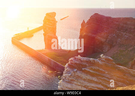 Die roten Sandsteinfelsen der deutschen Insel Helgoland mit der Formation "Lange Anna im warmen Abendlicht. Stockfoto