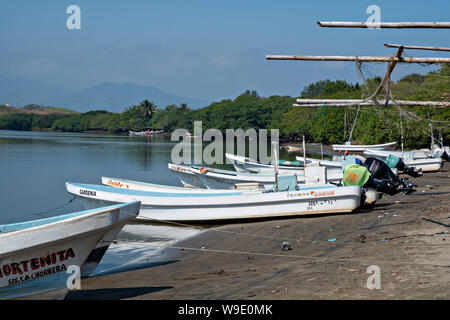 Fischerboote namens Pangas Strände am Rande des Sontecomapan Lagune bei La Barra de Sontecomapan, Veracruz, Mexiko. Die Lagune, die fliesst in den Golf von Mexiko ist eines der am besten erhaltenen Feuchtgebiete im Küstenbereich und Mangroven Wälder in Mexiko und ein Teil der Los Tuxtlas Biosphärenreservat. Stockfoto