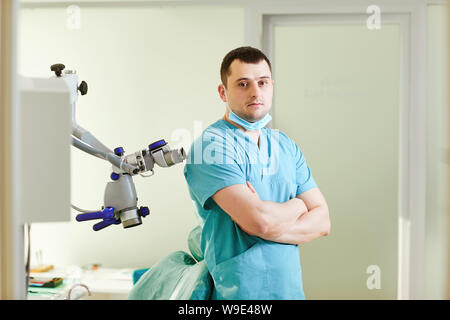 Ein männlicher Zahnarzt steht mit einem Mikroskop Stockfoto