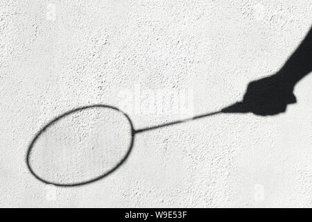 Schatten einer Badminton Schläger auf einer weißen Wand. Sport Konzept. Banbinton Schläger in der Hand. Kreative copyspace Stockfoto
