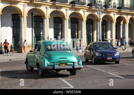 Havanna, Kuba - Januar 30, 2011: die Menschen zu Fuß durch die alten amerikanischen Autos in Havanna geparkt. Kuba hat eine der niedrigsten Auto - Pro-Kopf-Rate (38 pro 1000 Personen Stockfoto