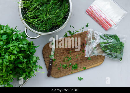 Verfügbare Paket mit gehackter frischer grüner Petersilie und Dill oder Fenchel auf grau Holztisch. Ansicht von oben. Kopieren Sie Platz. Ernte Konzept Stockfoto