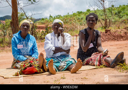 Drei Frauen Bauern auf einer Matte während einer partizipativen Gemeinschaft treffen im Norden Malawi sitzen. Stockfoto