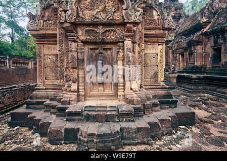Blinde Tür, Geländerpfosten und Devatas geschnitzt in den roten Sandsteinmauern in Banteay Srei Tempel von Angkor in Siem Reap, Kambodscha Stockfoto