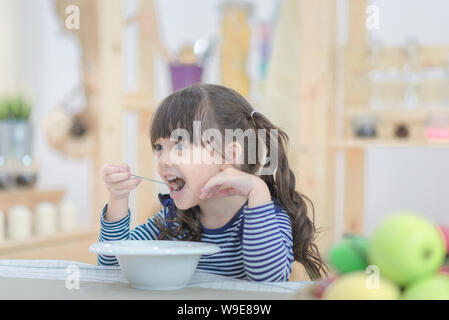 Süße kleine Mädchen essen Frühstück mit Cornflakes und Milch am Morgen. Foto serie von Familie, Kindern und glücklichen Menschen. Stockfoto