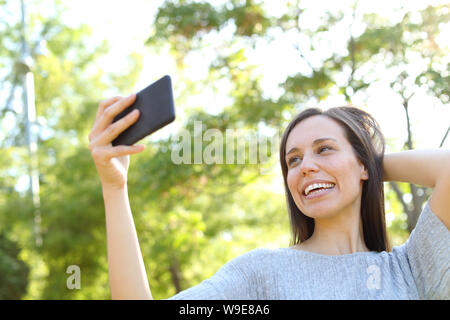 Glücklich nach Frau posiert unter selfies mit Smart Phone in einem Park Stockfoto