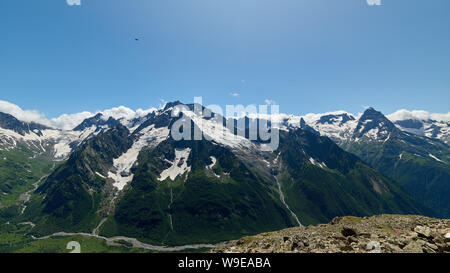 Berggipfel mit einem Gletscher und der Beginn einer Mountain Stream, fließt durch einen Pinienwald. Nördlicher Kaukasus, Russland Stockfoto