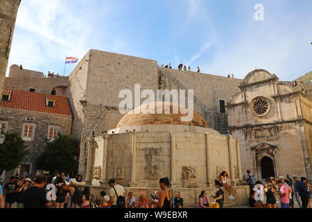 DUBROVNIK, KROATIEN - Juli 11,2019: Touristen Besuche großer Onofrio Brunnen und Kirche St. Saviour auf dem Platz in der Altstadt von Dubrovnik, Kroatien. Stockfoto