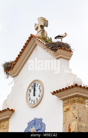 Nest einer Weißstorch (Ciconia ciconia) auf dem Dach der Kirche in der Altstadt in Olhao, Algarve, Portugal. Stockfoto