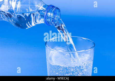 Das Gießen von Wasser im Glas aus Kunststoff Flasche Stockfoto