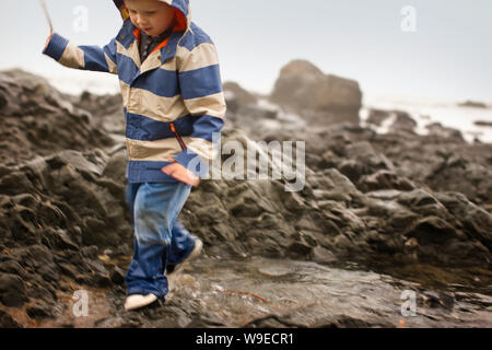 Ein Junge springt über gezeitenbecken am Strand. Stockfoto