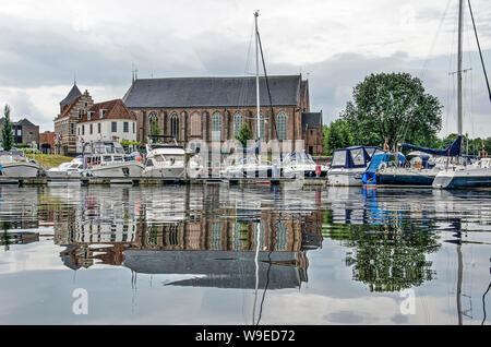 Vollenhove, Niederlande, 4. August 2019: Uferpromenade der Stadt und mehrere yackts im Wasser der Marina spiegeln Stockfoto