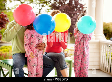 Humorvoller Blick auf Familie, bläst Luftballons. Stockfoto