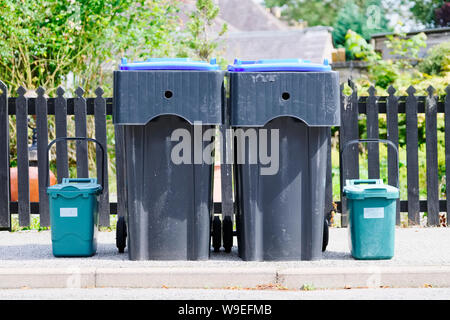 Green food Fächer und Schwarz wheelie Bins in ordentlich Zeile außerhalb von Haus und Garten Zaun Stockfoto