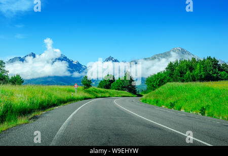 Asphalt unter den Feldern vor dem Hintergrund einer Berglandschaft. Stockfoto