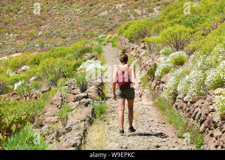 Mädchen mit Rucksack Spaziergänge entlang der Bergpfad. Eine Frau ist auf einem steinigen Weg in Teneriffa. Stockfoto