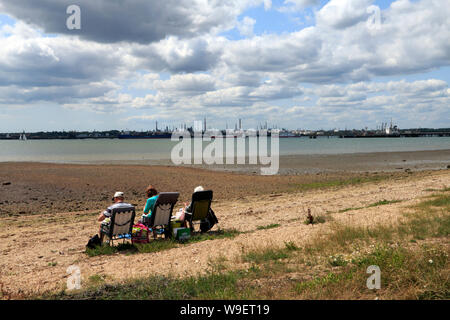 Die Leute am Strand bei Hamble-Le - Reis in Fawley Ölraffinerie in der Nähe von Southampton, England Stockfoto