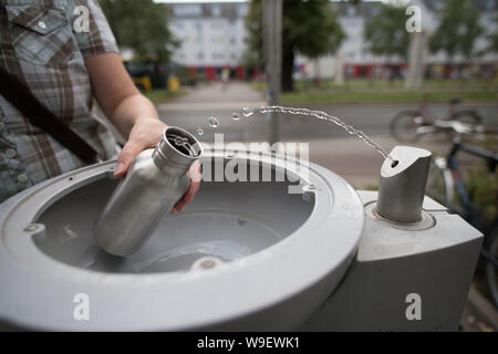 Berlin, Deutschland. 12 Aug, 2019. Ein Passant füllt seine Trinkflasche mit Wasser bei einer Berliner Wasserbetriebe Wasserspender. Quelle: Jörg Carstensen/dpa/Alamy leben Nachrichten Stockfoto