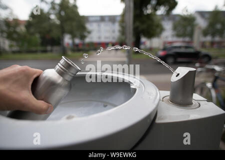 Berlin, Deutschland. 12 Aug, 2019. Ein Passant füllt seine Trinkflasche mit Wasser bei einer Berliner Wasserbetriebe Wasserspender. Quelle: Jörg Carstensen/dpa/Alamy leben Nachrichten Stockfoto